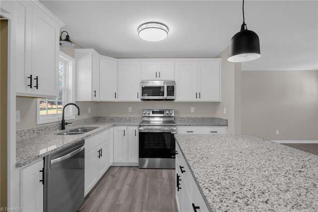 kitchen with sink, white cabinets, appliances with stainless steel finishes, and hanging light fixtures