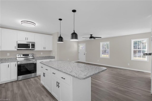 kitchen featuring hardwood / wood-style floors, stainless steel appliances, light stone countertops, a kitchen island, and white cabinets