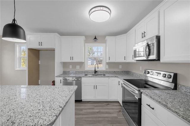 kitchen featuring sink, hanging light fixtures, light stone countertops, appliances with stainless steel finishes, and white cabinets