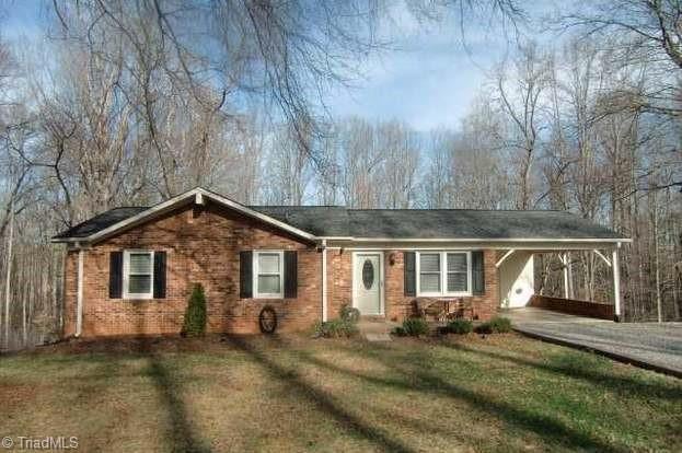 single story home featuring a front lawn and a carport