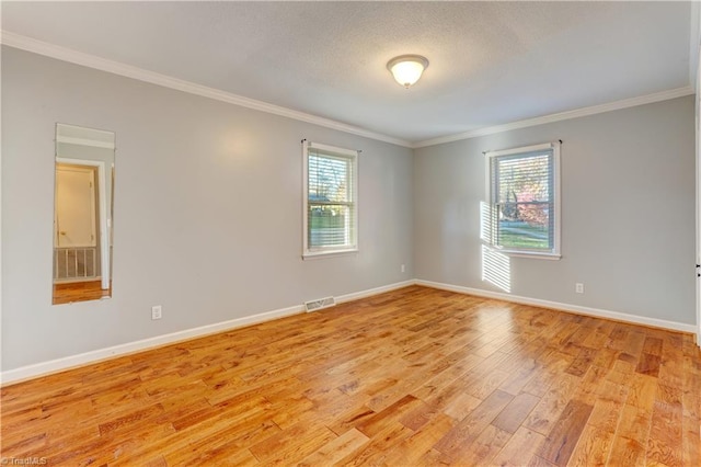 empty room with plenty of natural light, ornamental molding, and light hardwood / wood-style flooring