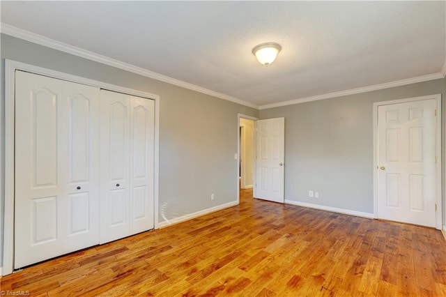 unfurnished bedroom featuring light hardwood / wood-style floors, ornamental molding, and a closet