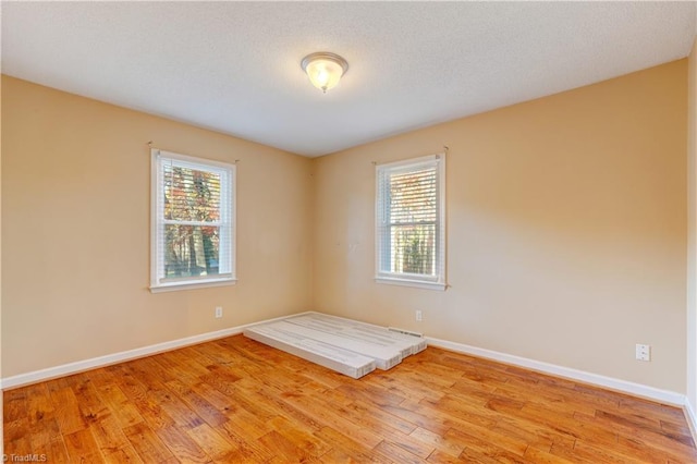 empty room with light hardwood / wood-style floors and a textured ceiling