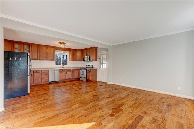 kitchen with ornamental molding, stainless steel appliances, light hardwood / wood-style floors, and sink