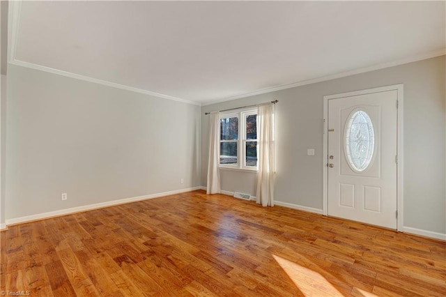 entrance foyer featuring ornamental molding, light wood-type flooring, and a healthy amount of sunlight