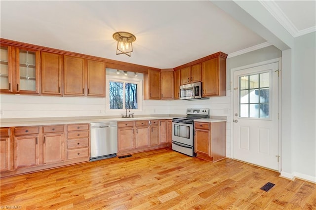 kitchen with tasteful backsplash, light hardwood / wood-style flooring, ornamental molding, and appliances with stainless steel finishes