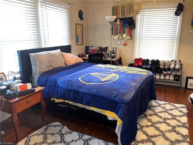 bedroom with multiple windows and dark wood-type flooring