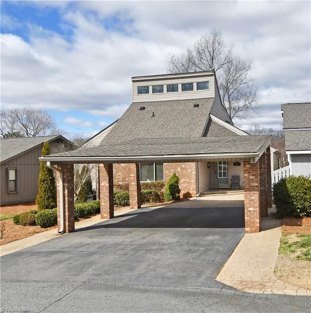 mid-century home featuring brick siding, driveway, and a shingled roof