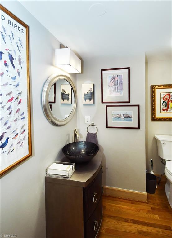 half bath featuring baseboards, toilet, wood finished floors, and vanity