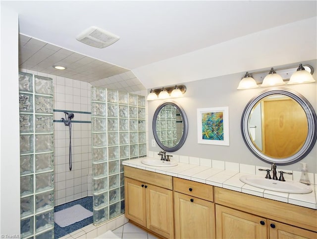 bathroom with double vanity, visible vents, a walk in shower, and a sink