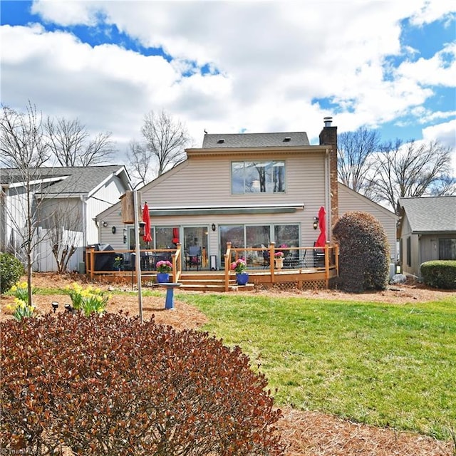 back of property with a deck, a yard, and a chimney