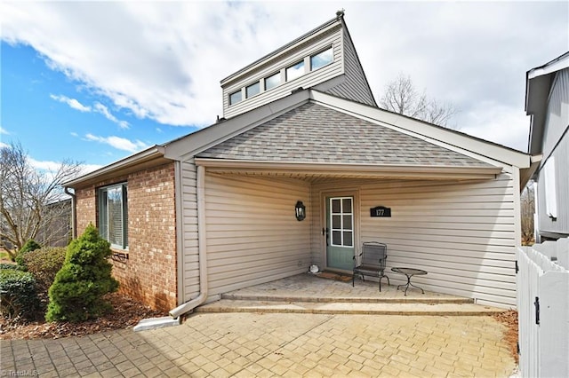 rear view of property featuring a patio area, brick siding, a shingled roof, and fence