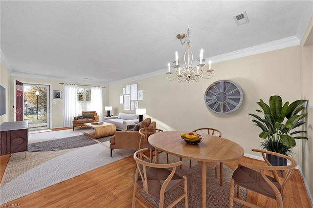 dining room featuring hardwood / wood-style floors, an inviting chandelier, and crown molding