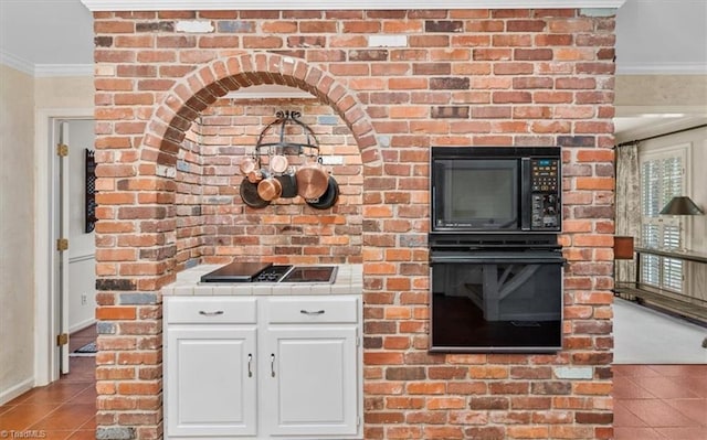 kitchen with black appliances, tile patterned flooring, ornamental molding, and white cabinets