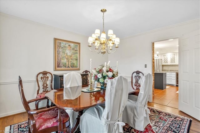 dining space featuring light wood-type flooring, crown molding, and a notable chandelier