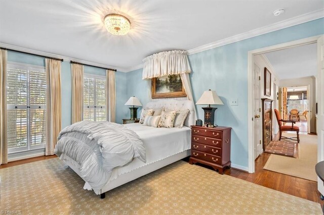 bedroom featuring multiple windows, wood-type flooring, and ornamental molding