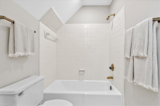 bathroom featuring toilet, vaulted ceiling, and tiled shower / bath combo