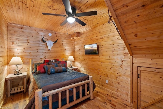 bedroom with ceiling fan, wood walls, wood-type flooring, and wooden ceiling