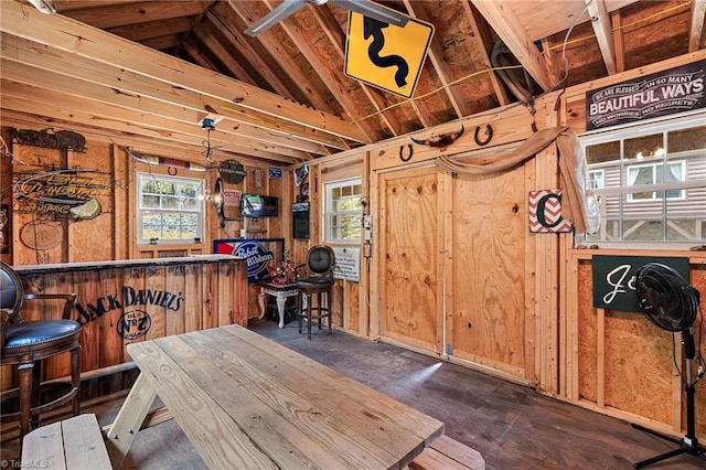 dining space with bar area, lofted ceiling, and wooden walls