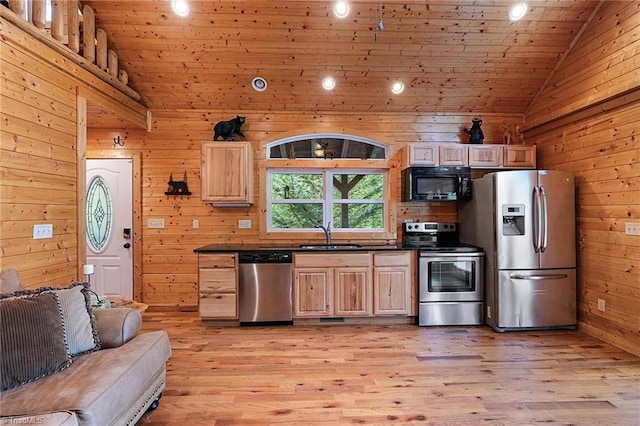 kitchen with wood walls, light brown cabinetry, sink, and appliances with stainless steel finishes