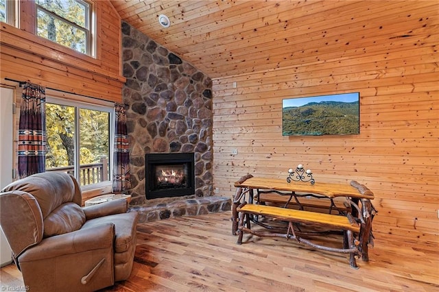 living room with wood ceiling, a stone fireplace, high vaulted ceiling, and light hardwood / wood-style floors