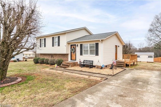 split level home featuring a front yard, brick siding, and a wooden deck