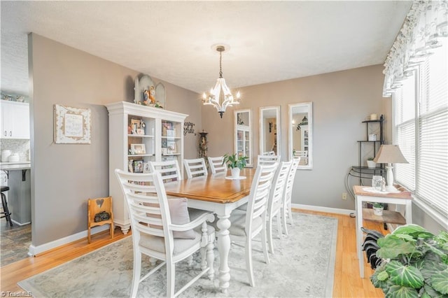 dining room featuring a chandelier, light wood-type flooring, and baseboards