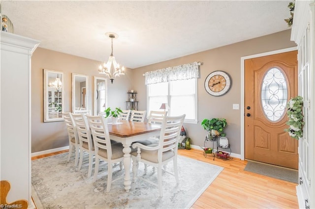 dining space with a chandelier, baseboards, and light wood finished floors