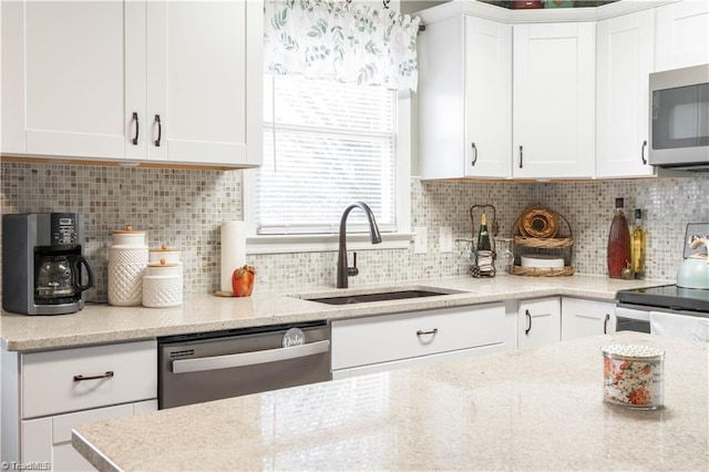 kitchen featuring stainless steel appliances, white cabinetry, a sink, and decorative backsplash