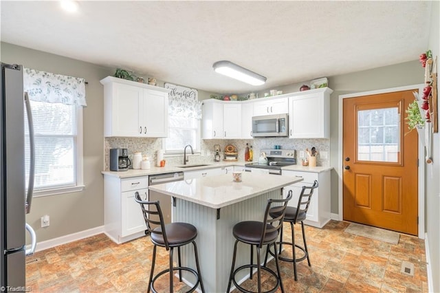 kitchen with light countertops, appliances with stainless steel finishes, a sink, and white cabinetry