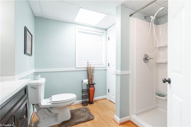 full bath featuring a stall shower, toilet, wood finished floors, vanity, and a paneled ceiling