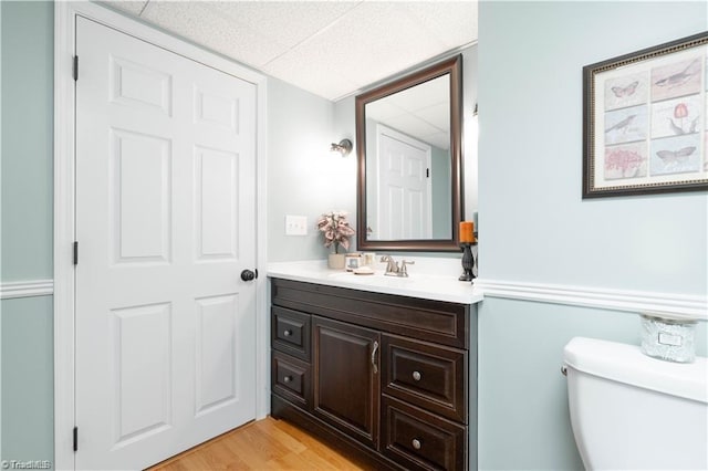 bathroom featuring a drop ceiling, vanity, toilet, and wood finished floors