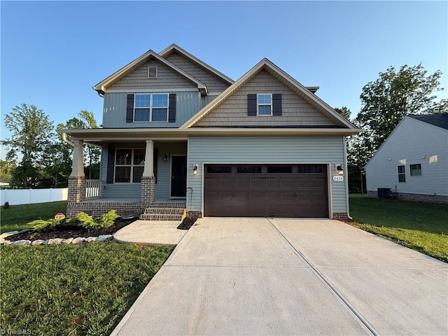 craftsman inspired home featuring a porch, a front lawn, concrete driveway, and central air condition unit