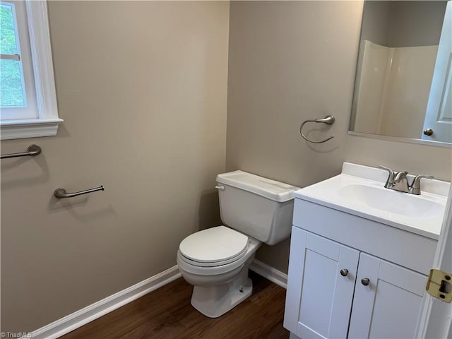 bathroom with toilet, baseboards, wood finished floors, and vanity