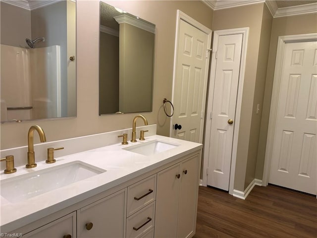 bathroom with a sink, ornamental molding, double vanity, and wood finished floors
