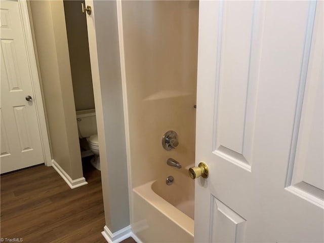 bathroom featuring toilet, baseboards, shower / tub combination, and wood finished floors