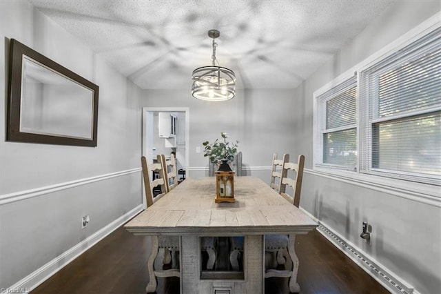 dining room with a notable chandelier, a textured ceiling, and dark hardwood / wood-style flooring