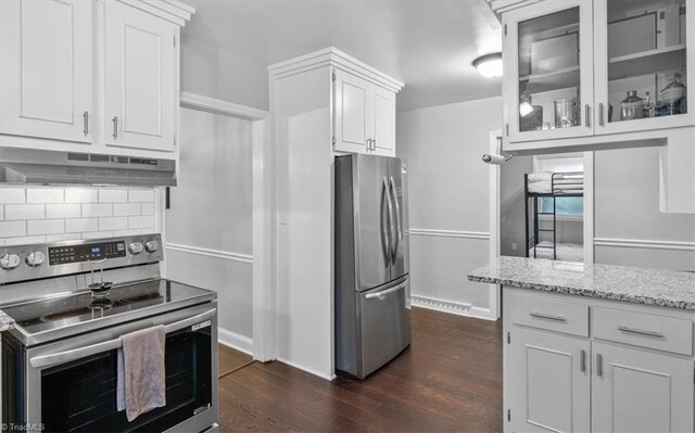 kitchen with stainless steel appliances, dark hardwood / wood-style flooring, white cabinetry, light stone counters, and tasteful backsplash