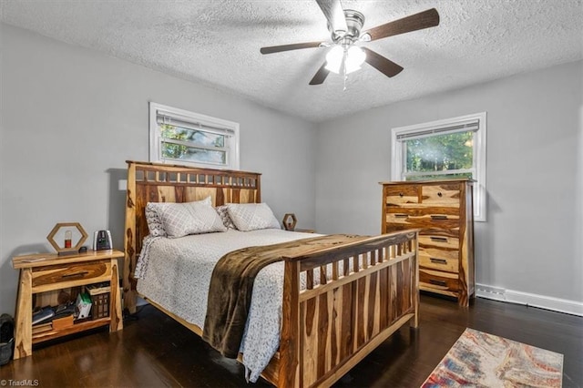 bedroom featuring dark wood-type flooring, ceiling fan, a textured ceiling, and multiple windows