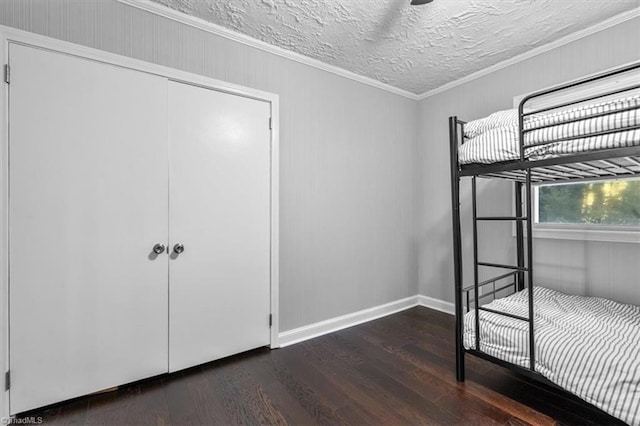 unfurnished bedroom with a closet, a textured ceiling, ornamental molding, and dark hardwood / wood-style flooring