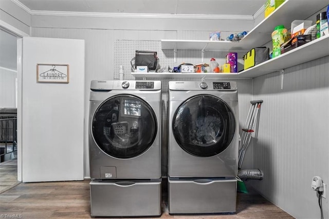 laundry area featuring crown molding, washing machine and clothes dryer, and hardwood / wood-style floors