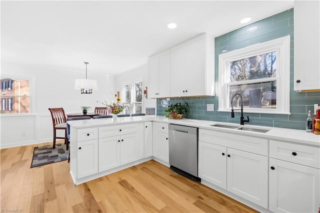 kitchen with stainless steel dishwasher, pendant lighting, sink, white cabinetry, and light hardwood / wood-style floors