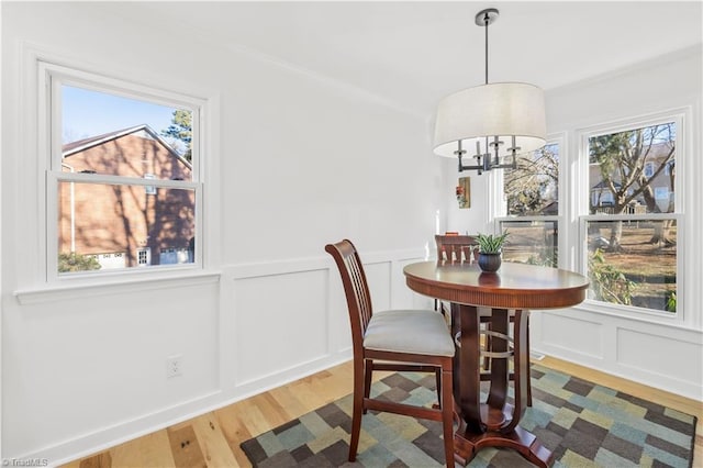 dining area with a chandelier, ornamental molding, plenty of natural light, and wood-type flooring