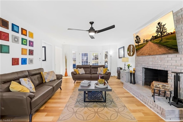 living room with ceiling fan, light hardwood / wood-style flooring, french doors, and a fireplace