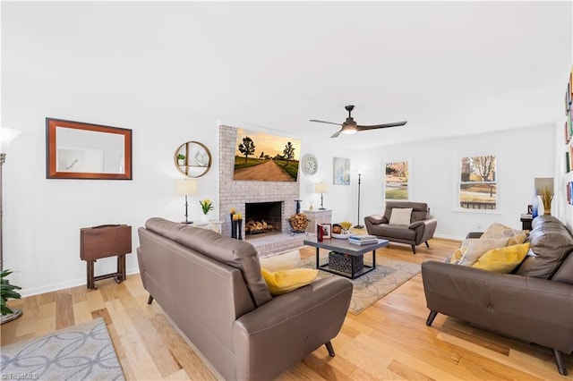 living room featuring a fireplace, light wood-type flooring, and ceiling fan