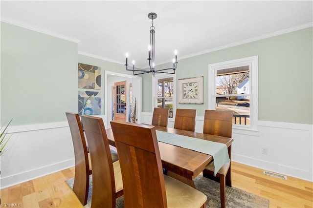 dining space featuring light wood-type flooring, a notable chandelier, and ornamental molding