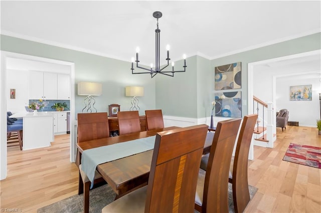 dining area with light hardwood / wood-style floors, ornamental molding, and a notable chandelier