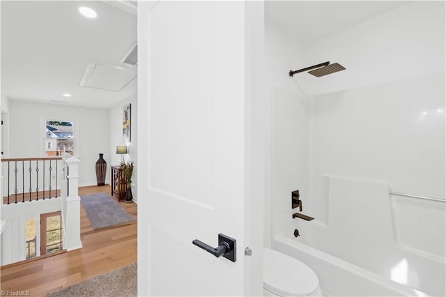 bathroom with hardwood / wood-style flooring, shower / bath combination, and toilet