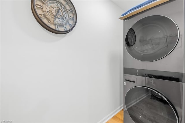 laundry room with stacked washer and clothes dryer and hardwood / wood-style floors