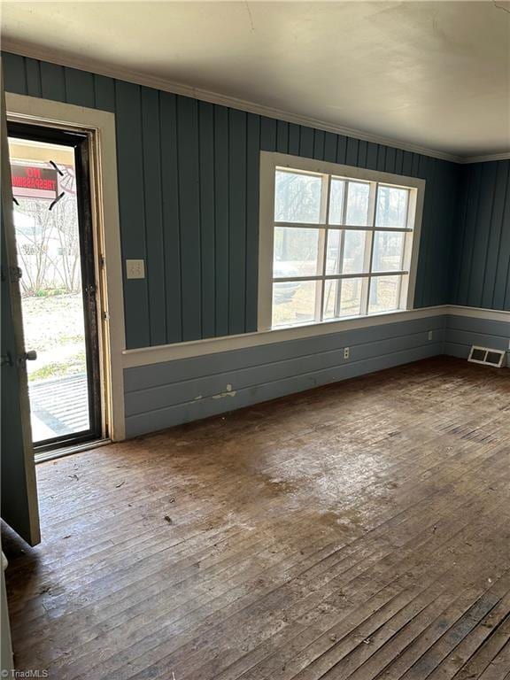 empty room featuring crown molding, visible vents, and hardwood / wood-style floors